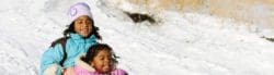 Two girls snow sledding