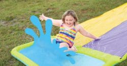 A girl sliding on a slip and sliding into a puddle of water